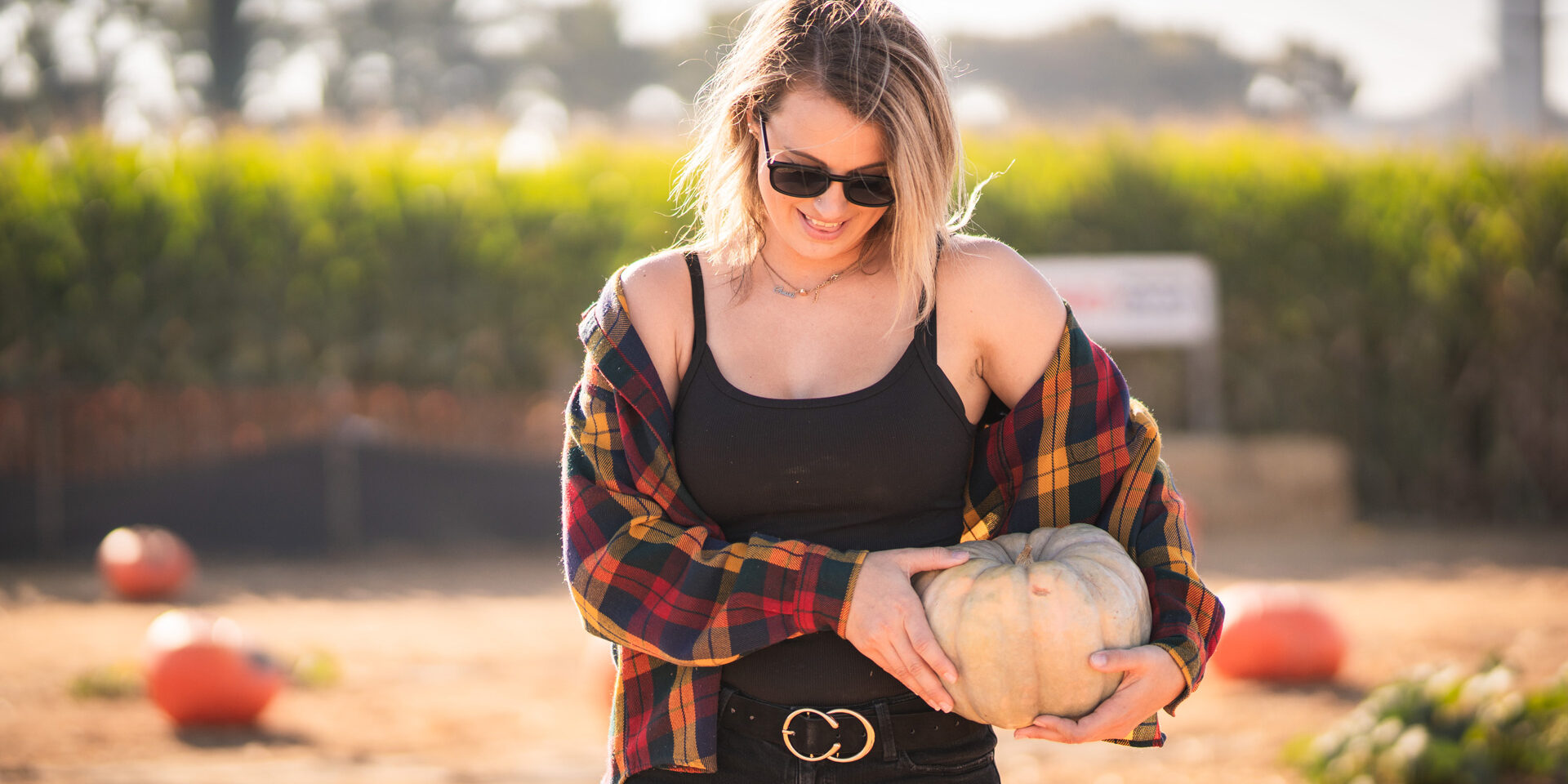 young woman picking a pumpkin at a local pumpkin patch